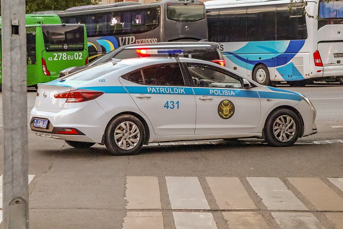 Патрульный автомобиль полиции Казахстана с включёнными проблесковыми маячками на городской улице