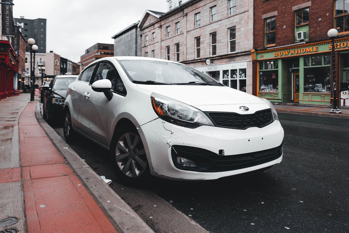 Белый Kia Rio на городской улице после дождя