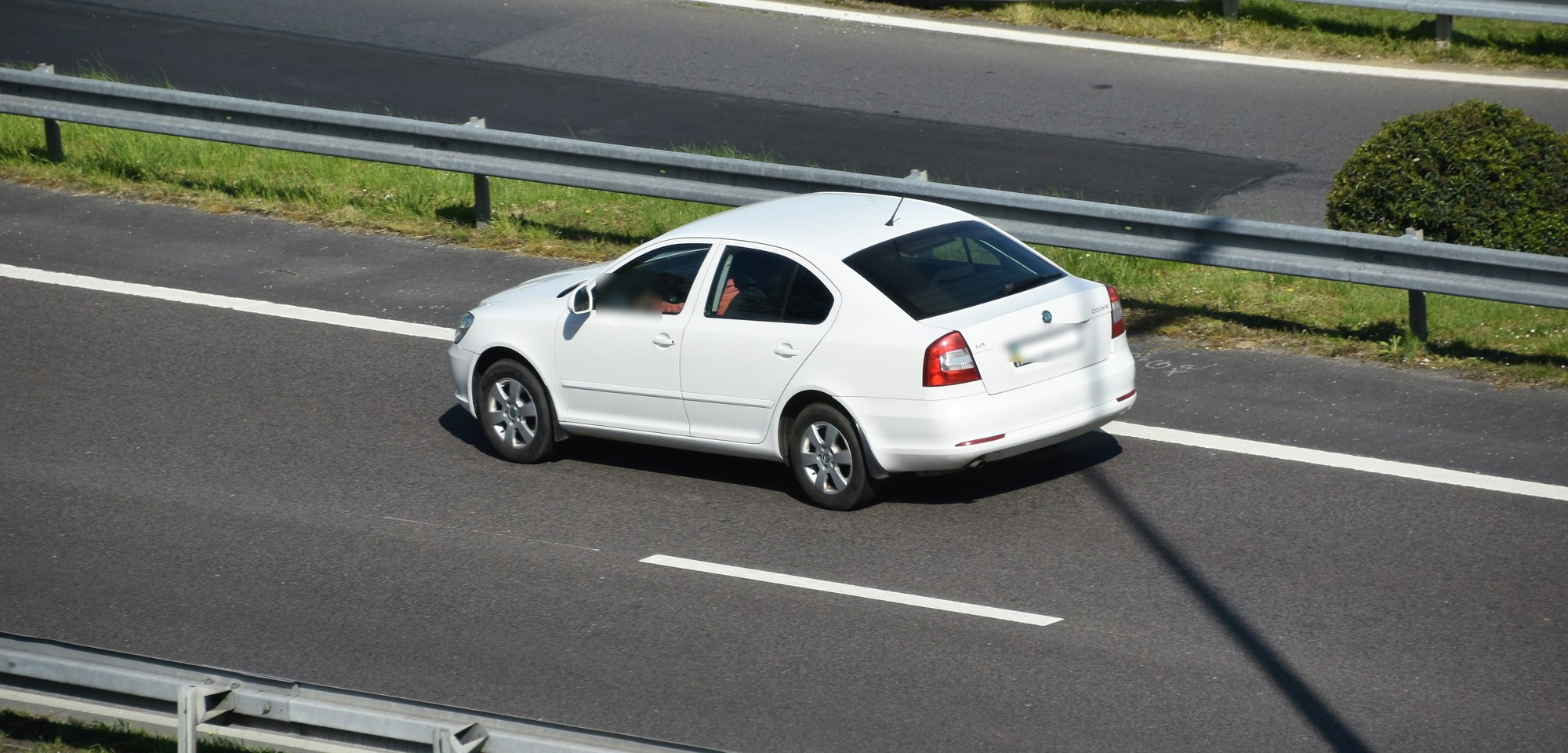 Skoda Octavia второго поколения, белый лифтбек на автостраде, вид сзади сбоку