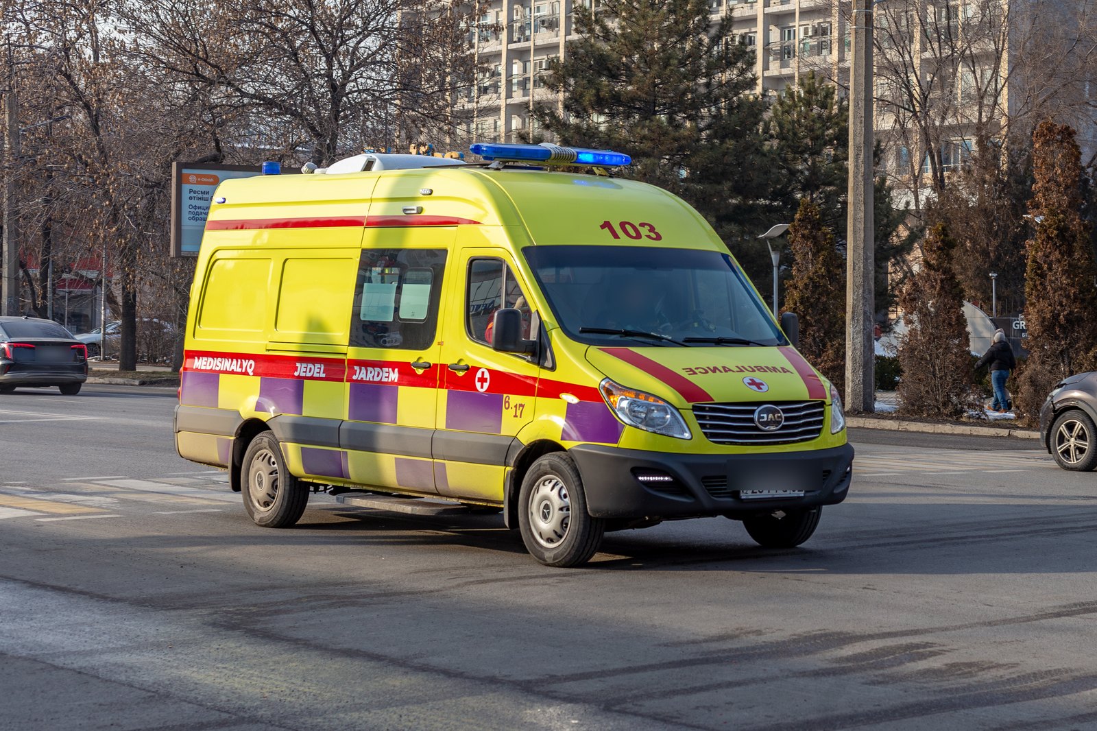 Автомобиль скорой помощи с включённым синим проблесковым маячком на улице в Алматы