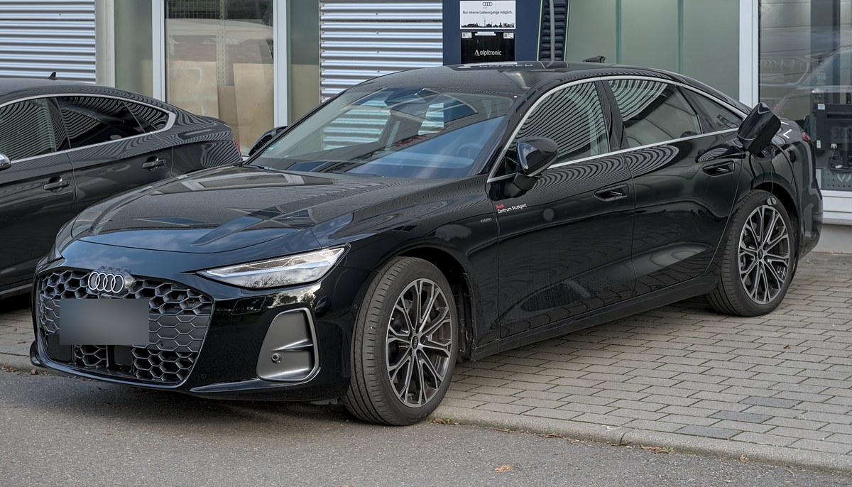 Чёрный седан Audi A6 C9, вид спереди слева, у дилерского центра