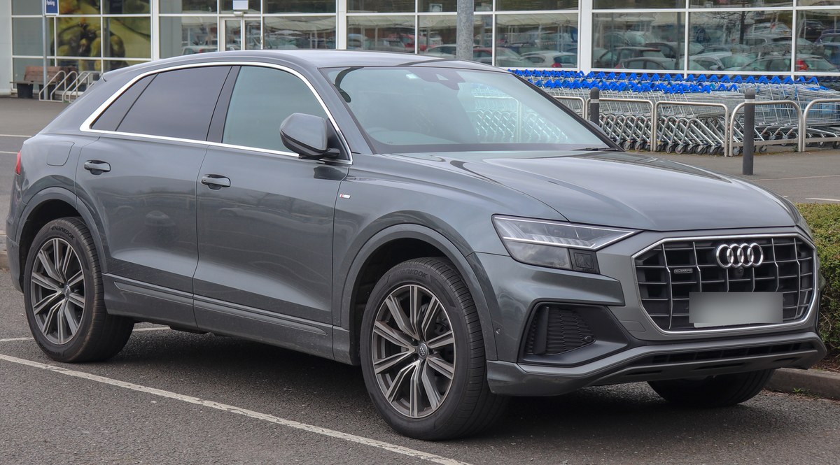Серый Audi Q8 S line, вид спереди справа, на парковке