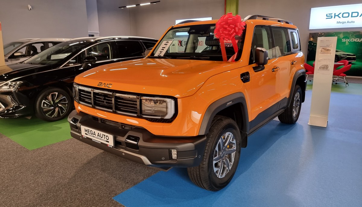 Оранжевый рамный внедорожник BAIC BJ40 второго поколения, вид спереди сбоку, в дилерском салоне в Румынии