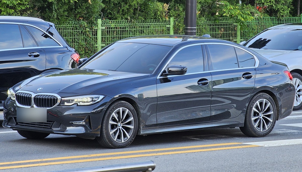 BMW 3 серии G20 седан, вид спереди сбоку: чёрный BMW 320i (G20) на городской улице