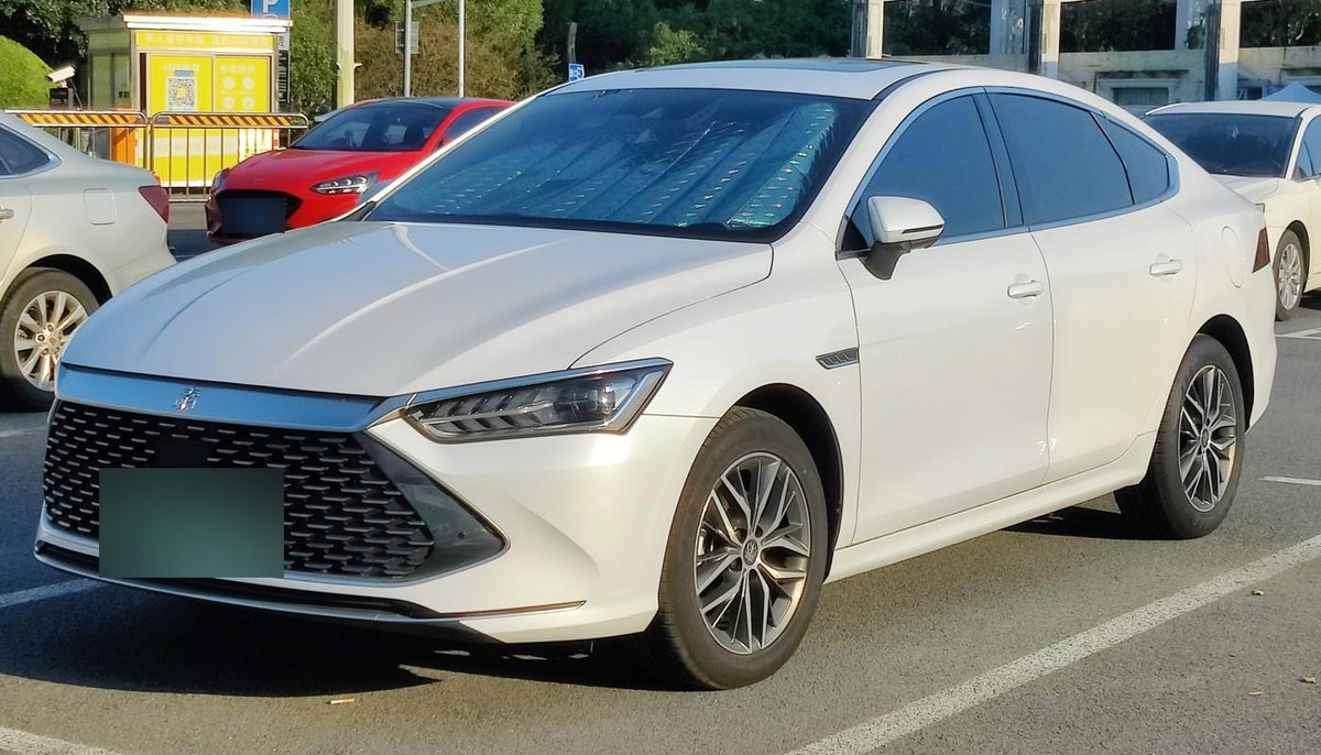 Белый седан BYD Qin Plus DM-i 2021 года, вид спереди сбоку, на парковке в Шанхае