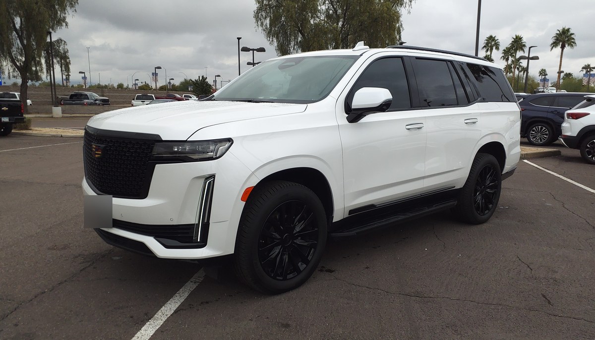 Белый Cadillac Escalade пятого поколения, вид спереди слева в три четверти, на парковке дилера