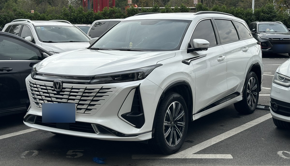Белый кроссовер Changan CS75 Plus поколения 2023 года, вид спереди в три четверти на парковке
