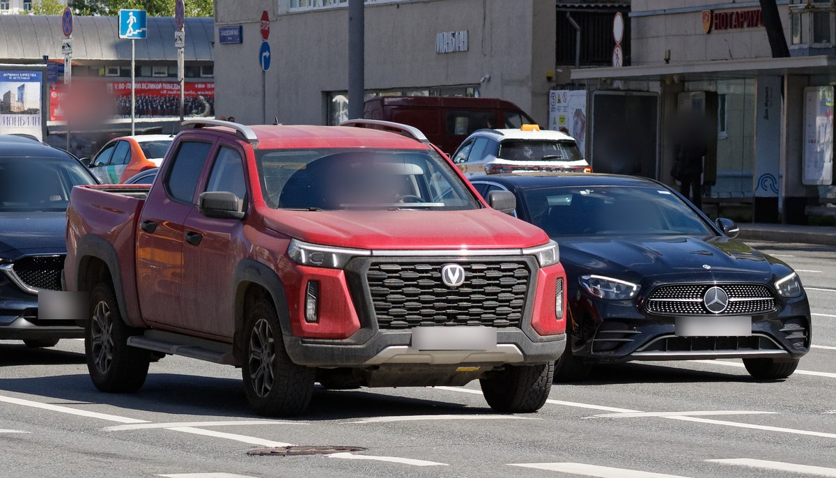 Красный пикап Changan Hunter Plus, вид спереди в три четверти на городском перекрёстке