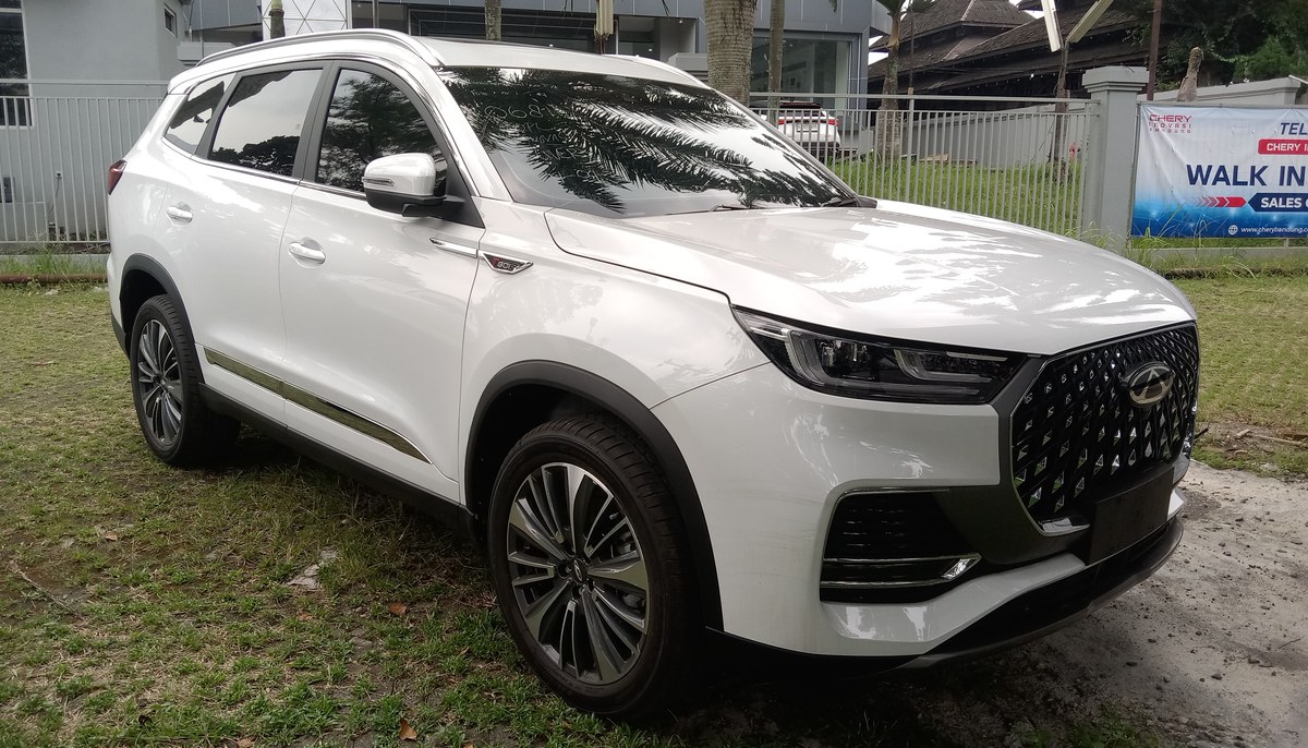 Белый Chery Tiggo 8 Pro Max, вид спереди справа, на площадке с рекламным баннером