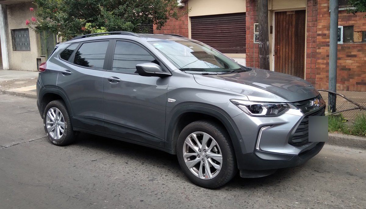 Серый кроссовер Chevrolet Tracker второго поколения, вид спереди сбоку, на городской улице