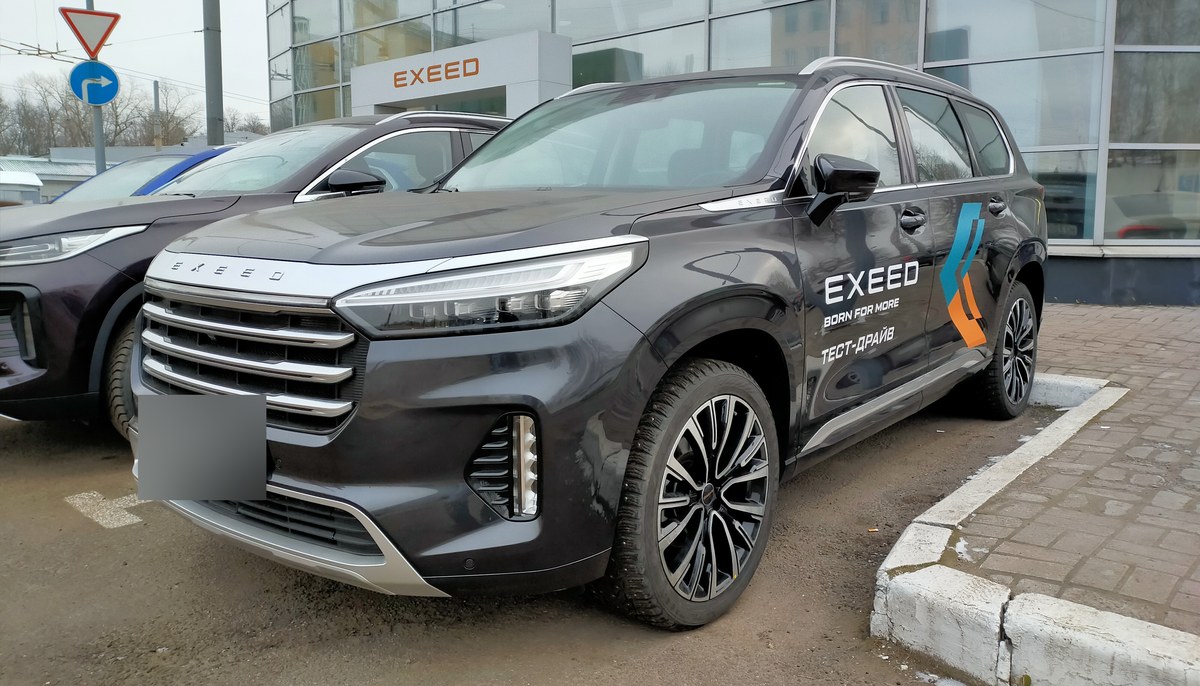 Тёмно-серый Exeed VX до обновления с горизонтальной решёткой, вид спереди сбоку, у дилерского центра