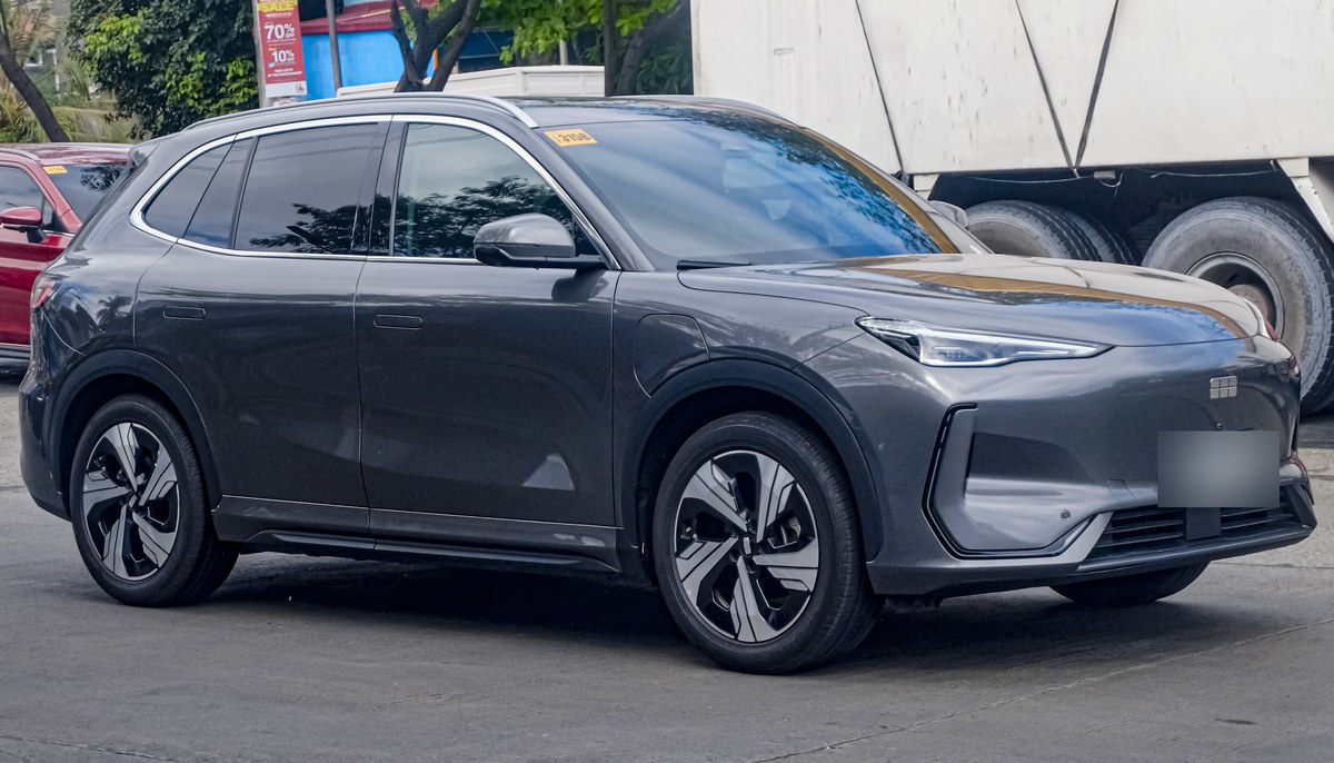 Серый электрический кроссовер Geely EX5 Max, вид спереди в три четверти, на городской улице на Филиппинах