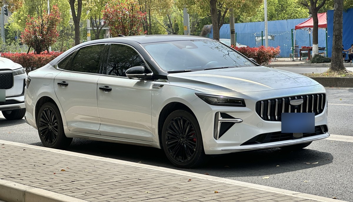Белый седан Geely Preface L с чёрной крышей, вид спереди сбоку, на городской парковке в Китае