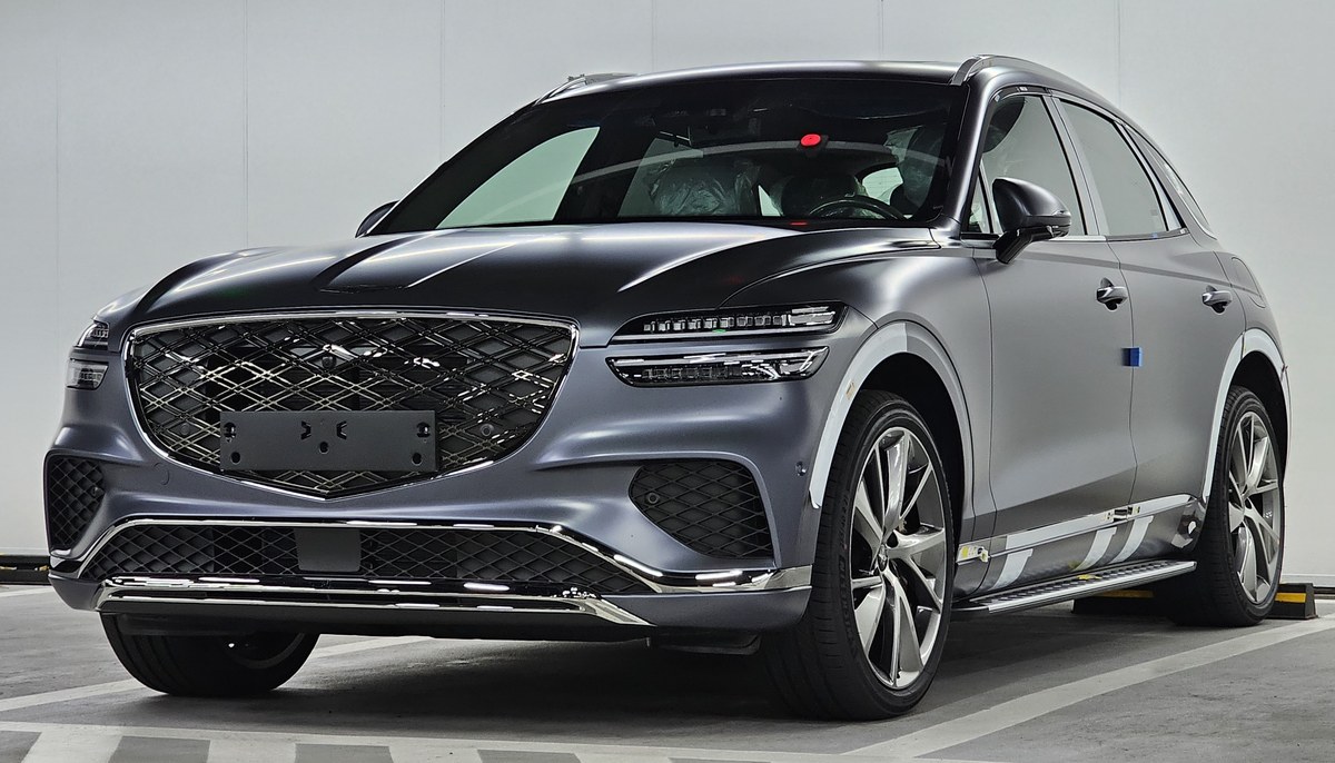 Genesis GV70 после рестайлинга в матовом сине-сером цвете, вид спереди в три четверти, в студии