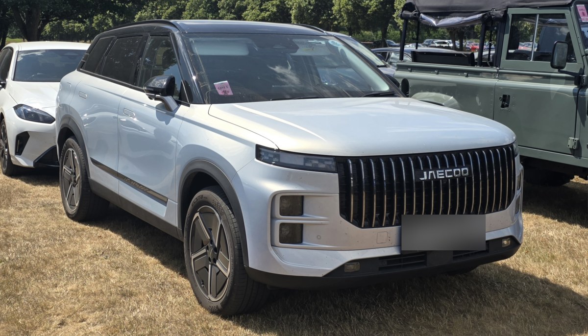 Серебристо-белый Jaecoo 7 PHEV с чёрной крышей на выставке, вид спереди сбоку
