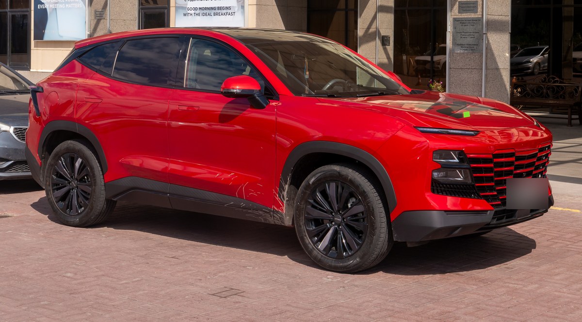 Красный кроссовер Jetour Dashing на парковке у здания в Астане, вид спереди справа