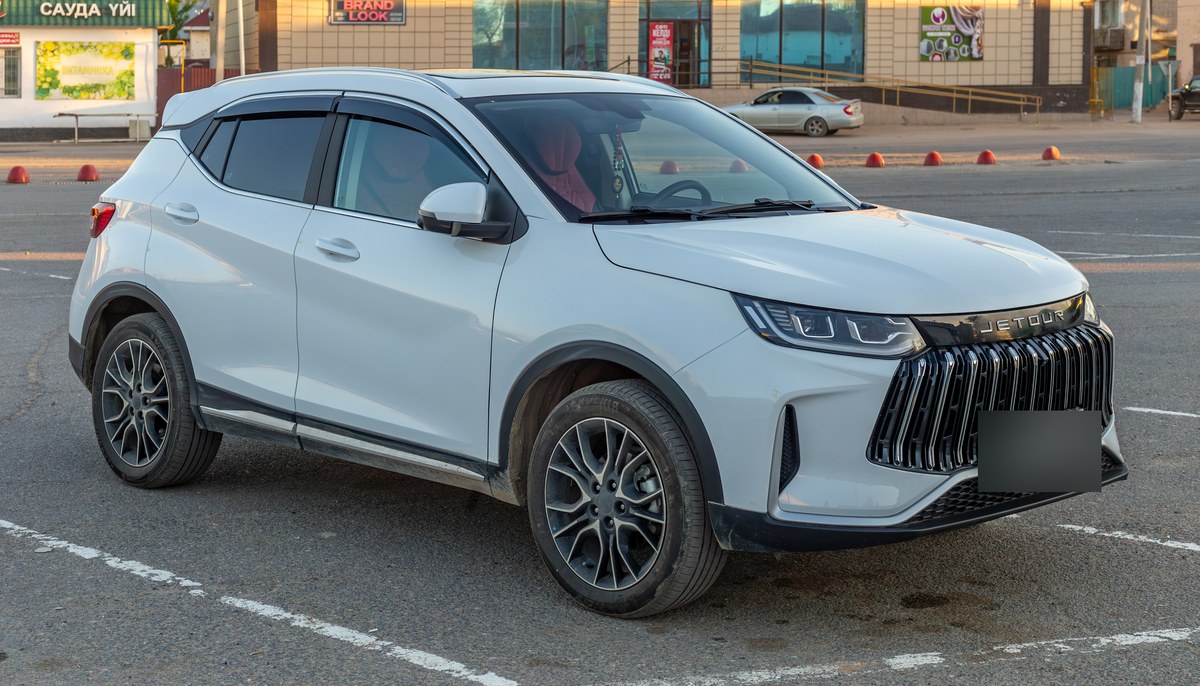 Белый Jetour X50, вид спереди справа, на парковке в посёлке Торетам, Казахстан