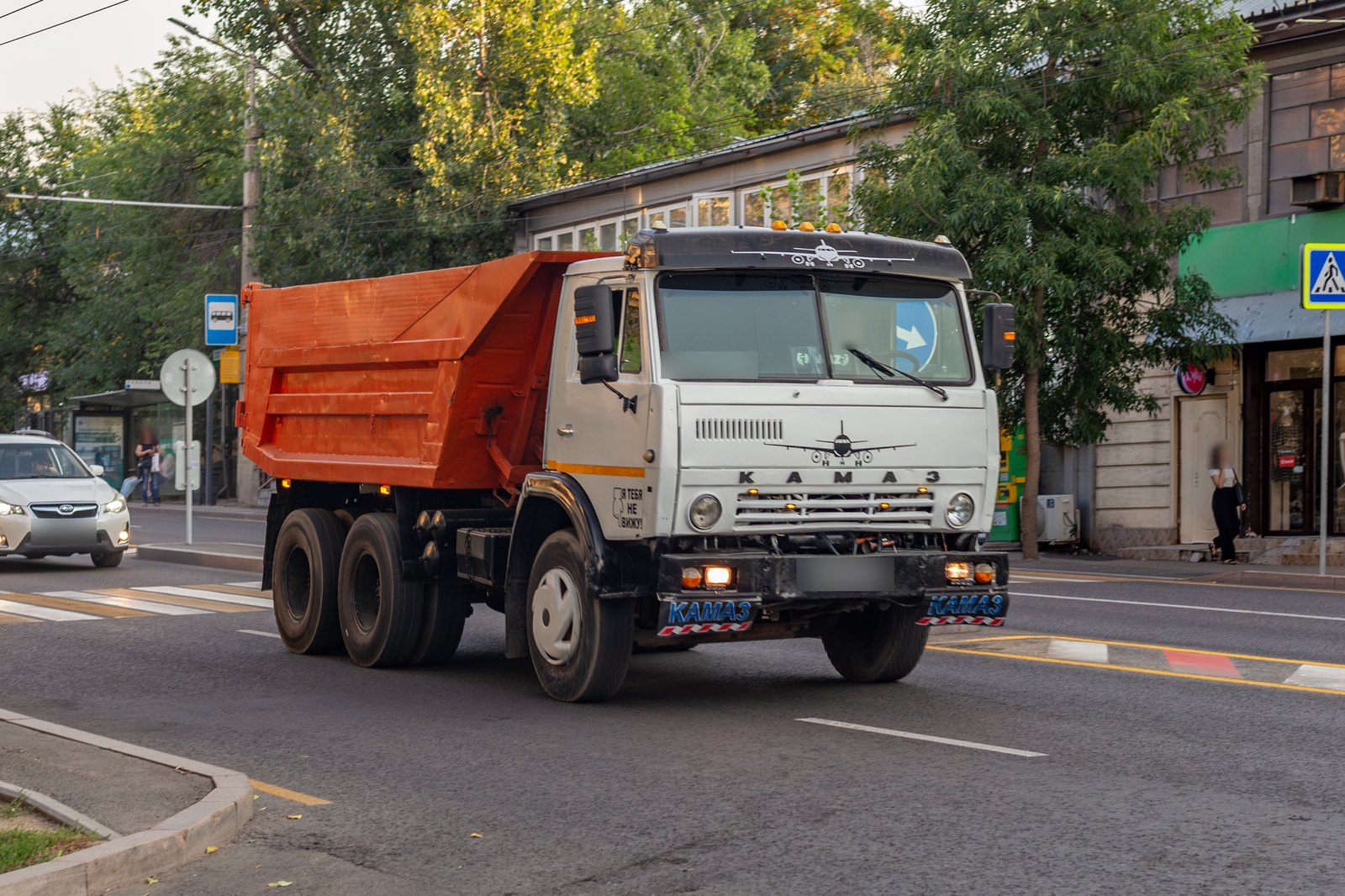 Самосвал КамАЗ-55111 с оранжевым кузовом на улице в Алматы