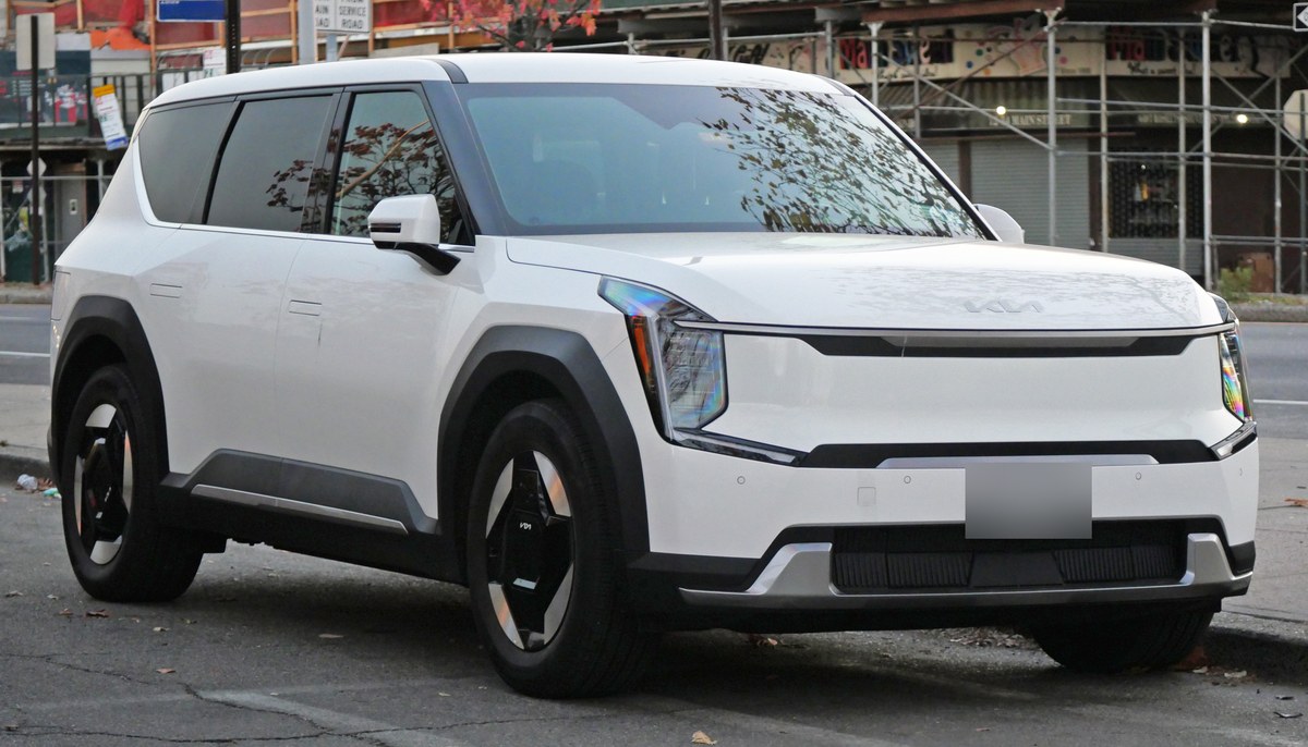 Белый электрический внедорожник Kia EV9 с трёхрядным салоном, вид спереди в три четверти