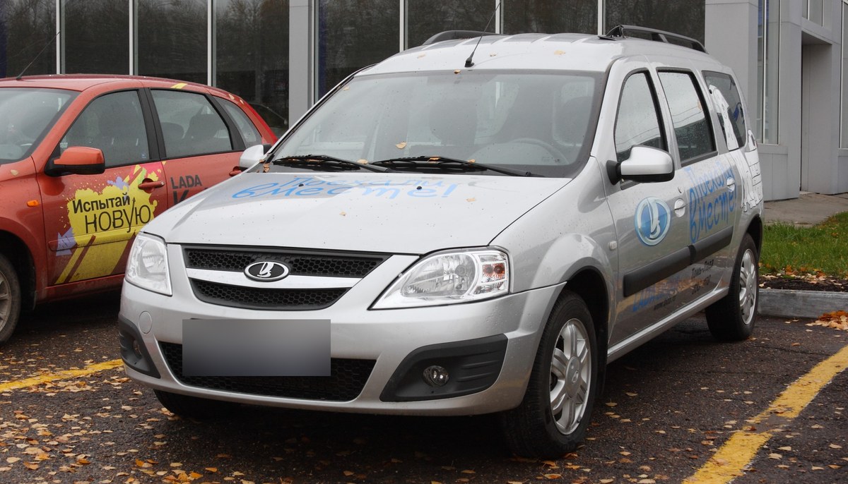 Серебристый универсал Lada Largus первого поколения, вид спереди сбоку, у автосалона в Томске