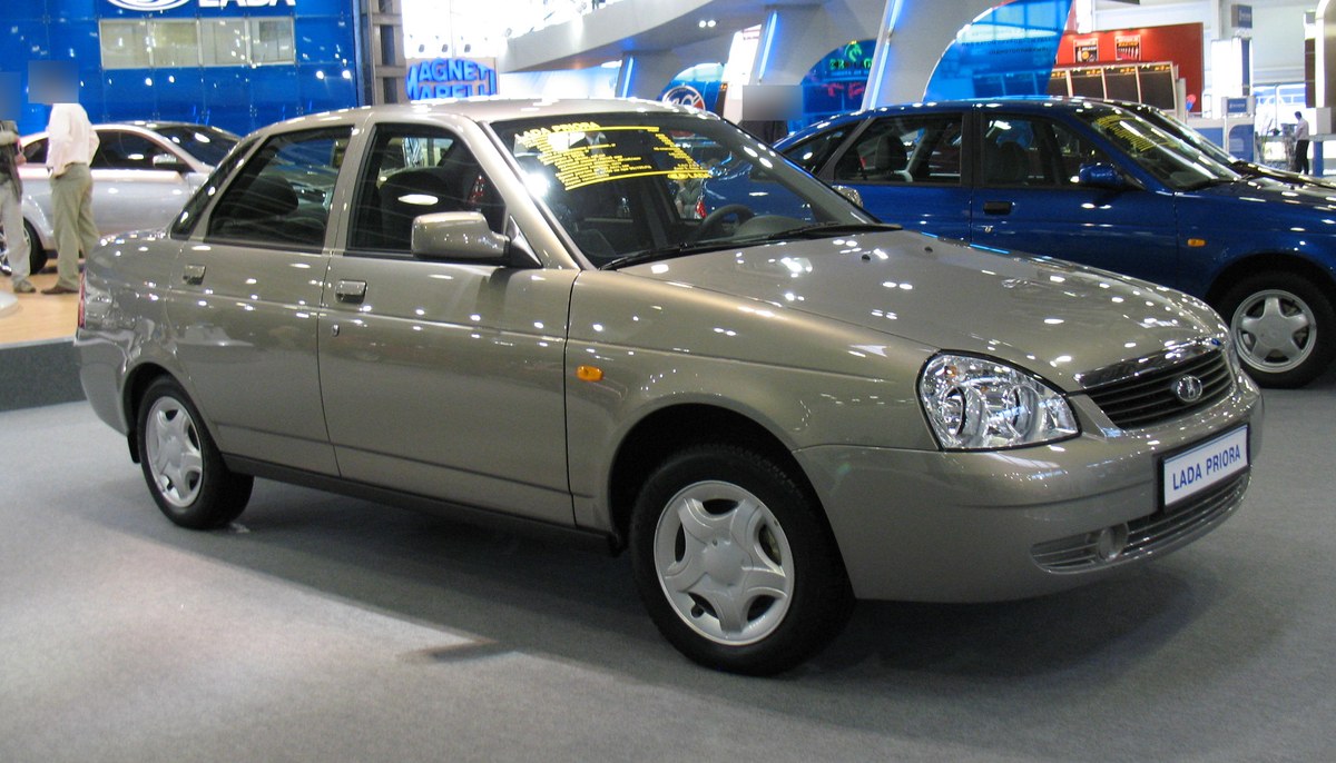Бежевая Lada Priora седан на стенде LADA на автосалоне, вид спереди три четверти