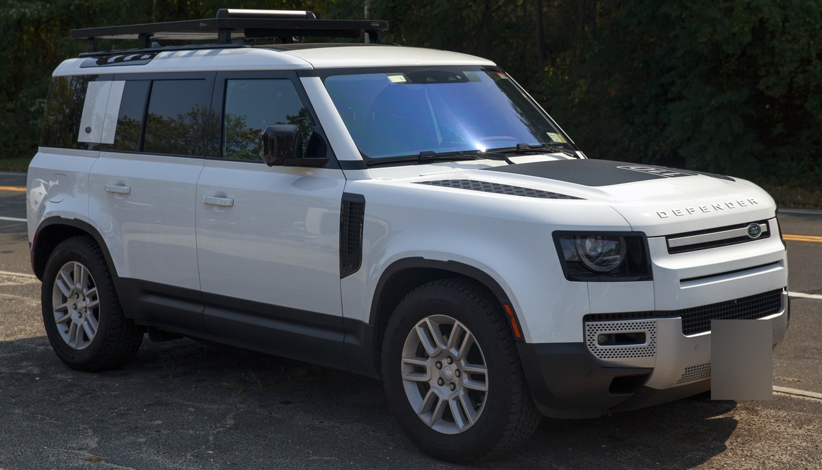 Белый Land Rover Defender 110 с багажником на крыше, вид спереди справа в три четверти