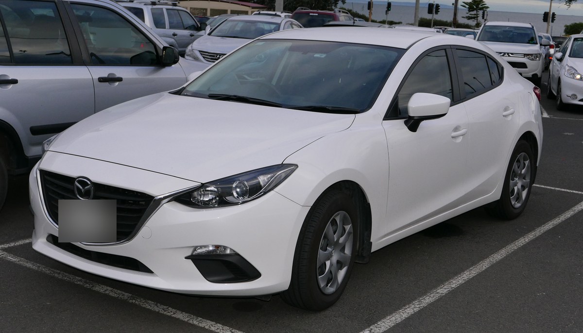 Белая Mazda3 третьего поколения (BM), седан, вид спереди в три четверти
