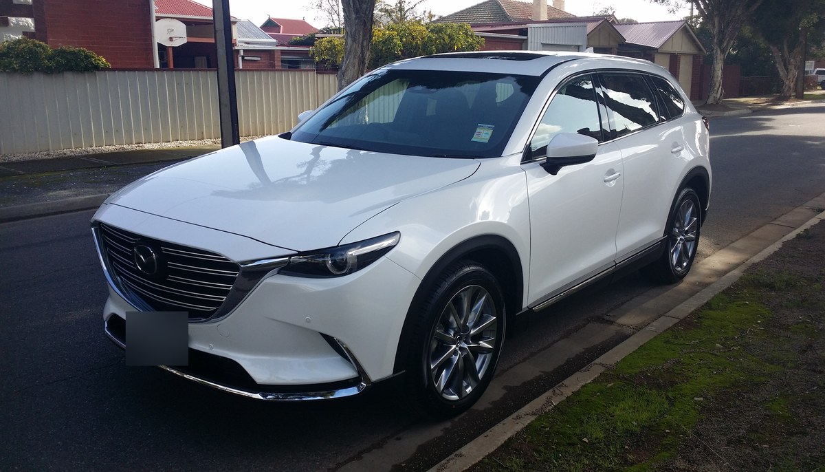 Белая Mazda CX-9 второго поколения (TC), вид спереди в три четверти на городской улице