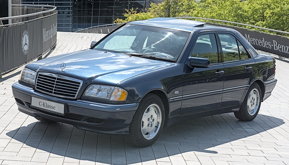 Тёмно-синий Mercedes-Benz C-Class W202 седан, вид спереди слева в три четверти, на выставочной площадке
