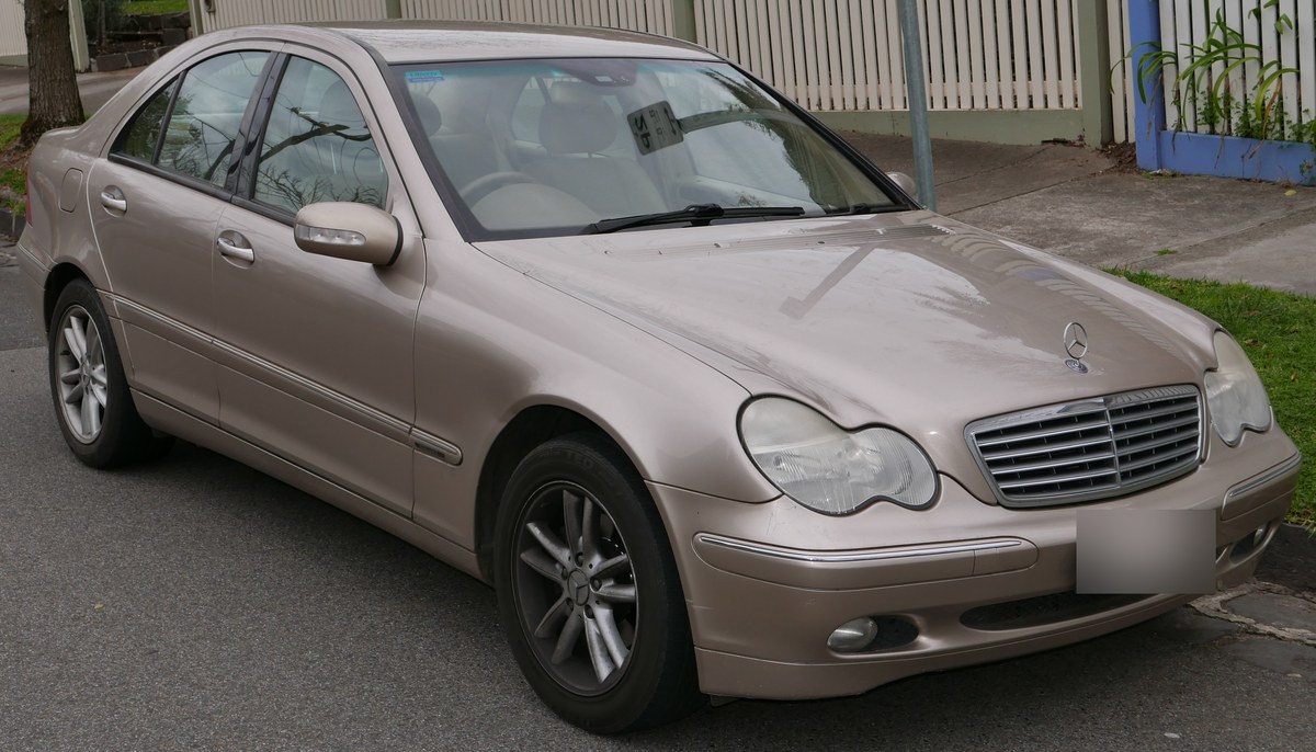 Бежевый Mercedes-Benz C-Class W203 седан до рестайлинга, вид спереди справа в три четверти, на городской улице