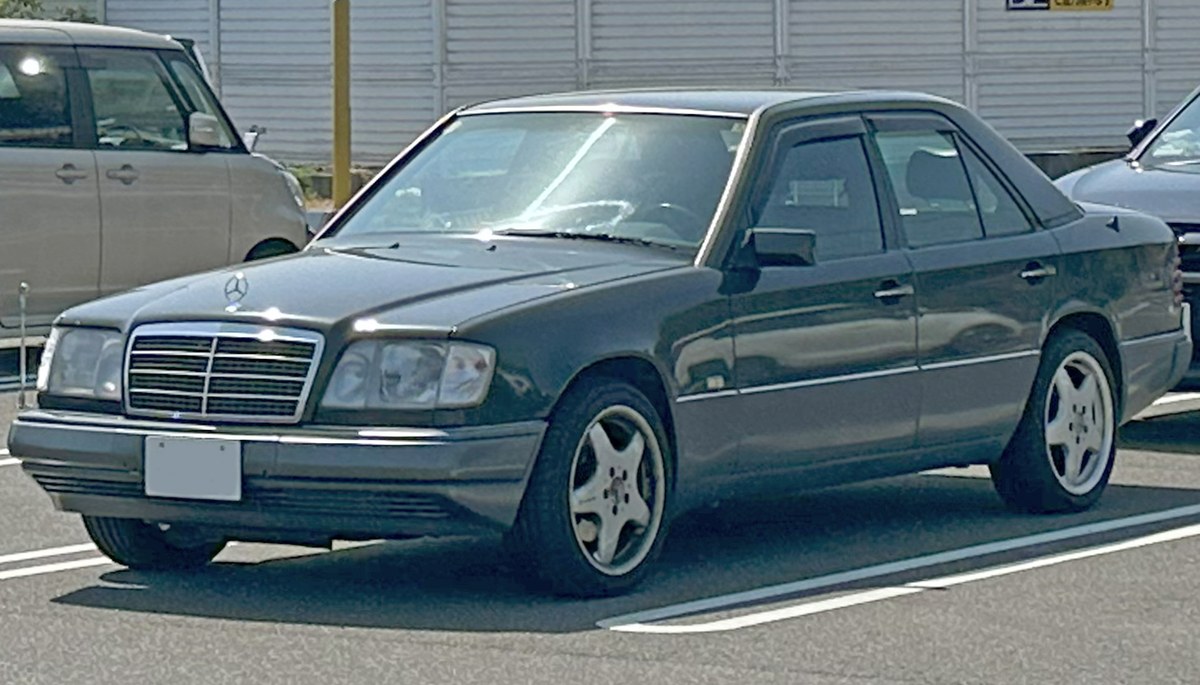 Тёмно-зелёный Mercedes-Benz E-Class W124 седан, вид спереди слева в три четверти, на парковке