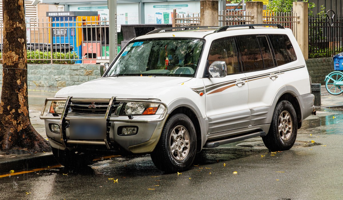Белый Mitsubishi Pajero третьего поколения с кенгурятником на городской улице, вид спереди сбоку