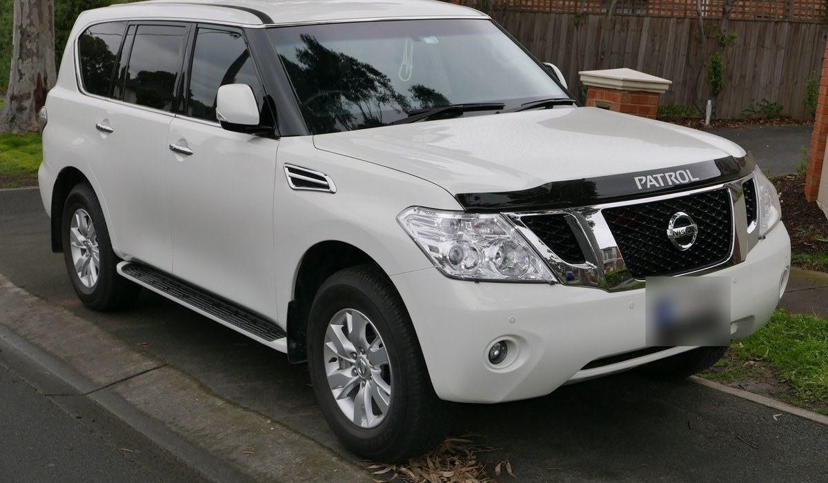 Белый Nissan Patrol Y62 на улице, вид спереди сбоку