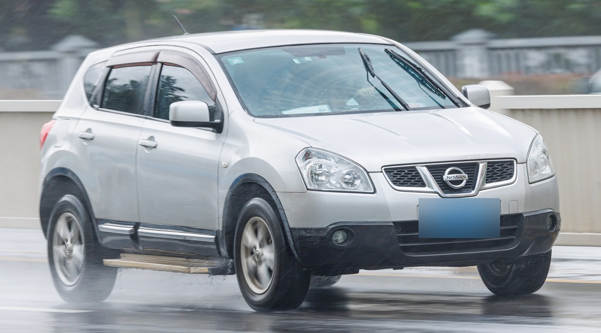 Серебристый Nissan Qashqai первого поколения (J10) в движении, вид спереди в три четверти