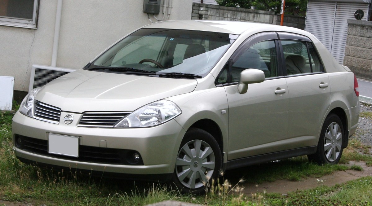 Бежевый Nissan Tiida первого поколения (C11), седан, вид спереди в три четверти