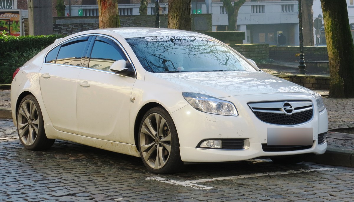Белый Opel Insignia первого поколения с обвесом OPC Line, вид спереди справа, на городской улице