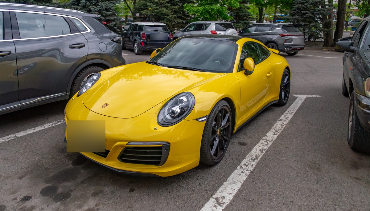 Жёлтый Porsche 911 Carrera поколения 991.2 на парковке в Алматы, вид спереди сбоку