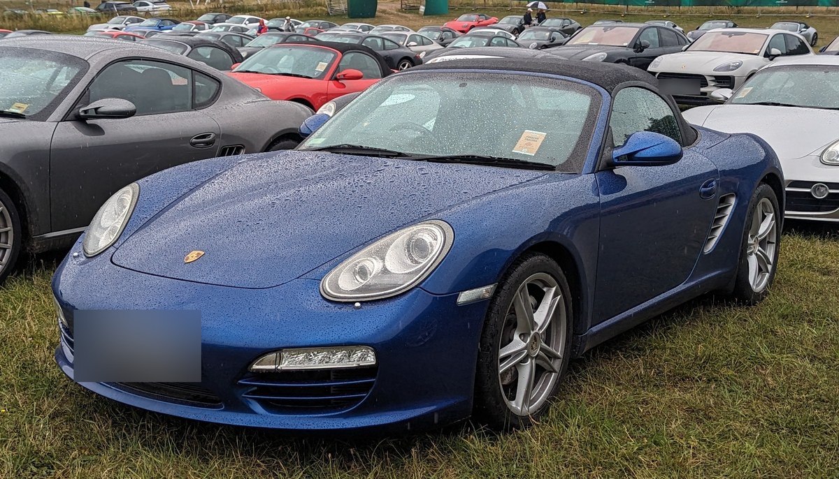 Синий Porsche Boxster S поколения 987 на стоянке автомобилей Porsche, вид спереди сбоку, Великобритания