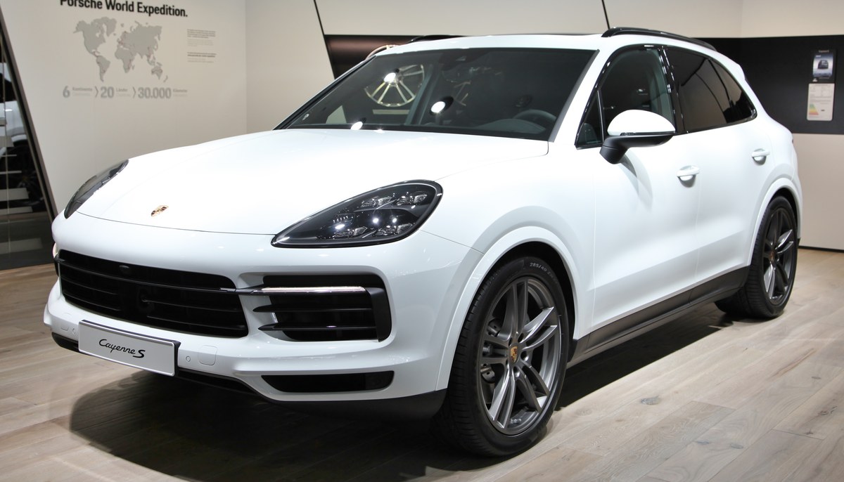 Белый Porsche Cayenne S третьего поколения, вид спереди в три четверти, на стенде автосалона