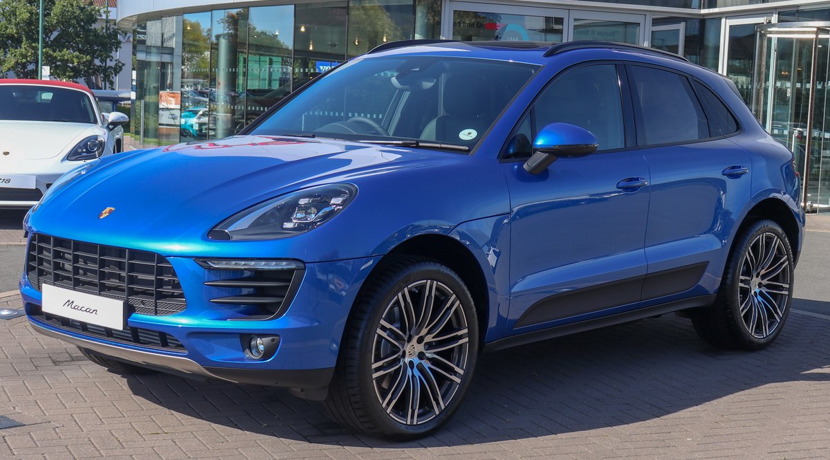 Синий Porsche Macan первого поколения с бензиновым мотором, вид спереди в три четверти, у дилера
