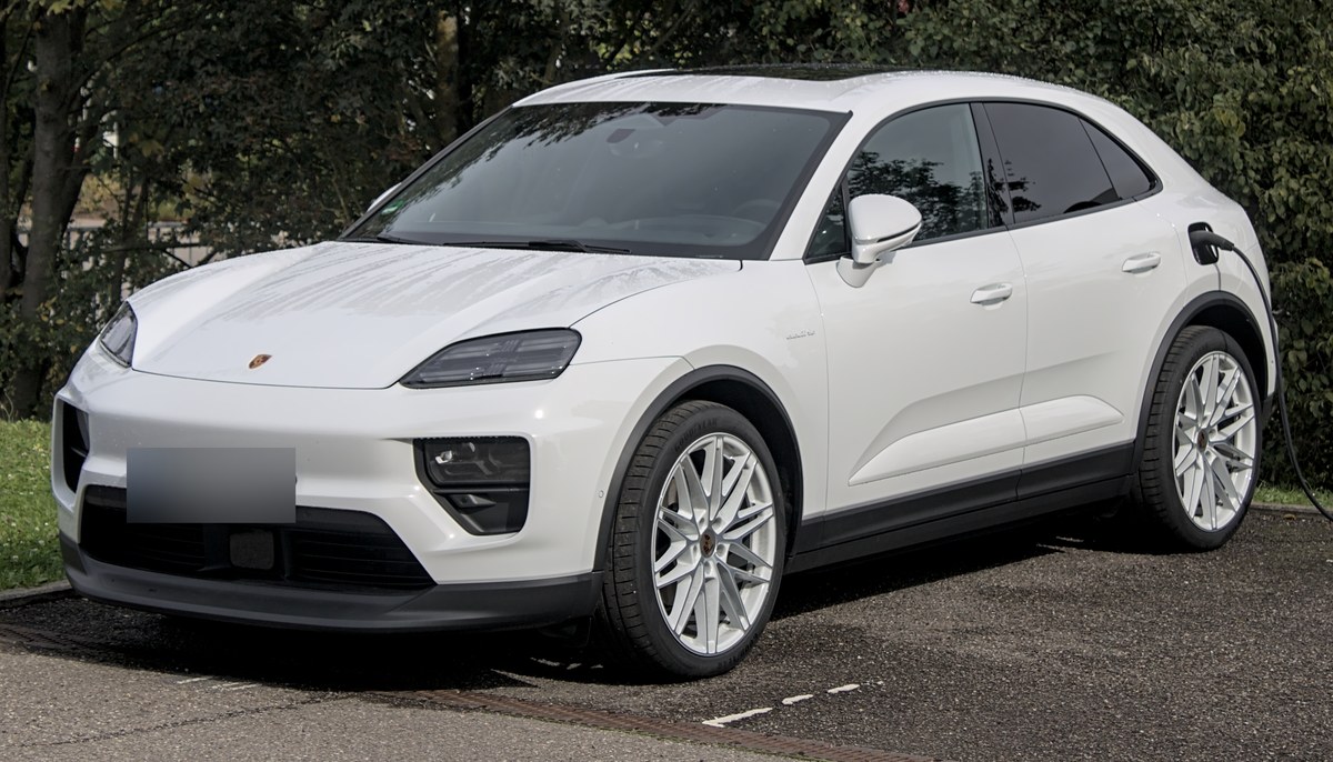 Белый Porsche Macan Electric (версия Macan 4) на зарядной станции, вид спереди в три четверти