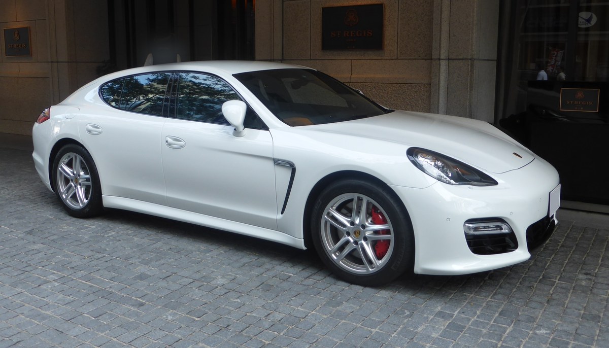 Белый Porsche Panamera первого поколения, вид спереди в три четверти, у входа в отель