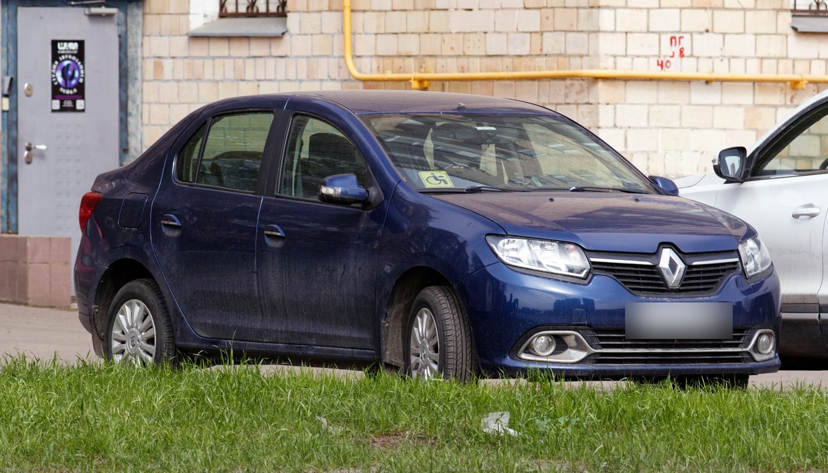 Синий седан Renault Logan II до рестайлинга, вид спереди справа, на газоне