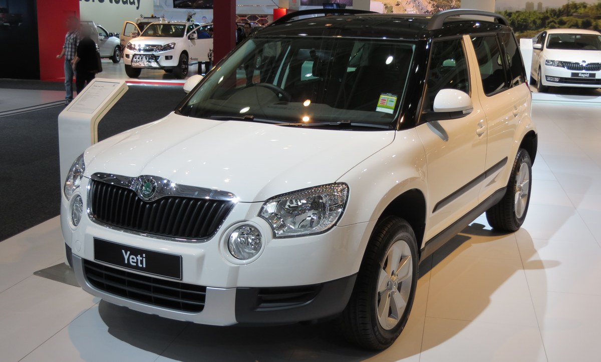 Белый кроссовер Skoda Yeti с чёрной крышей на выставочном стенде, вид спереди сбоку