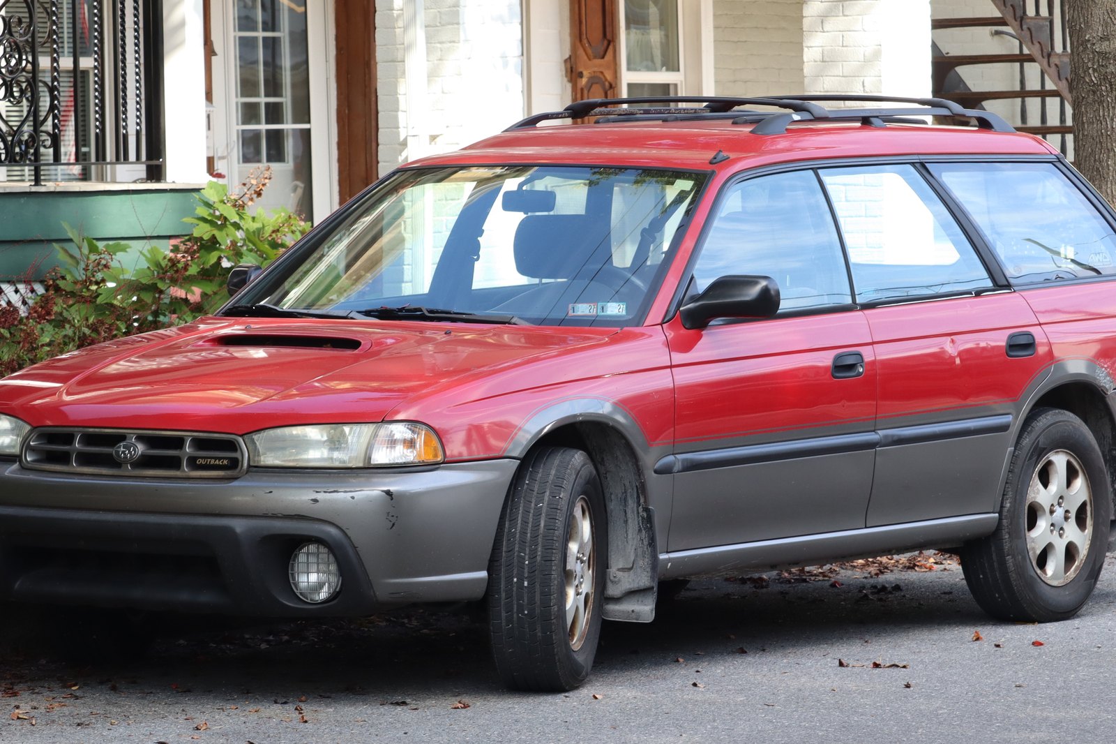 Красный универсал Subaru Legacy Outback 1999 года у тротуара