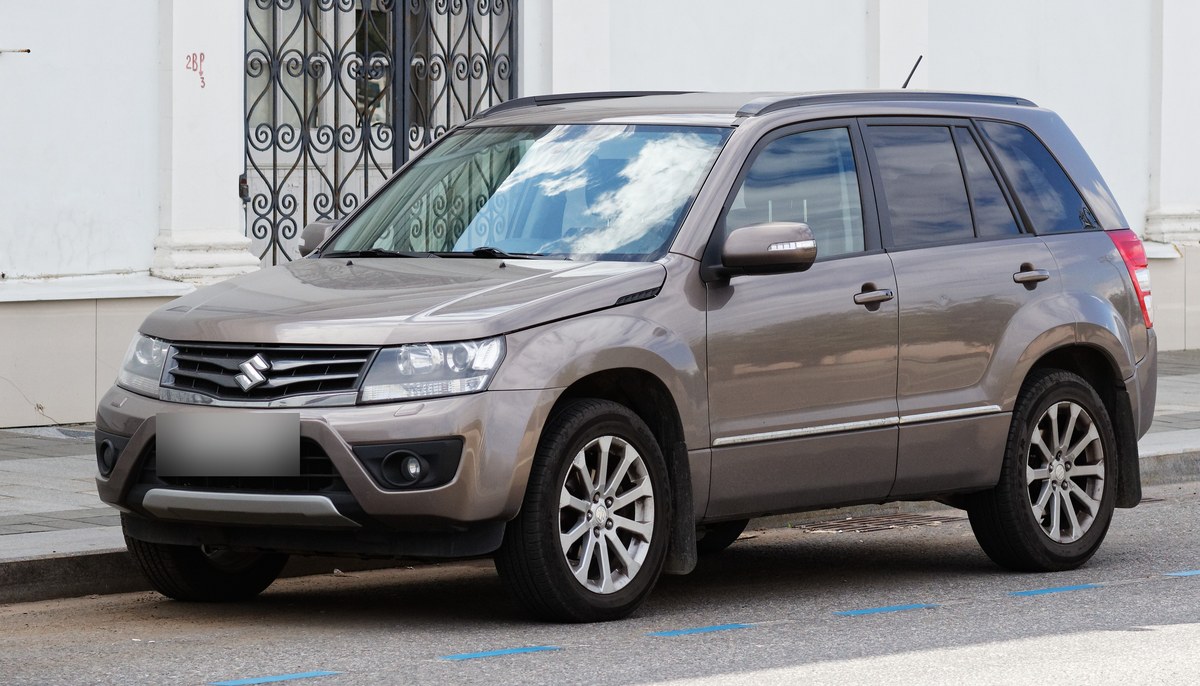 Коричнево-бежевый Suzuki Grand Vitara JT после рестайлинга, пятидверный, вид спереди слева, у бордюра