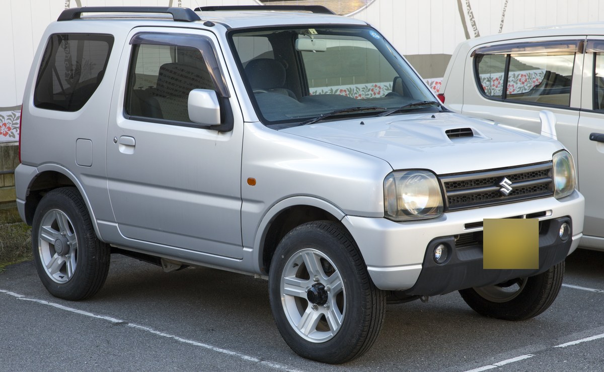 Серебристый Suzuki Jimny XC JB23 с японским номером, вид спереди справа, на парковке