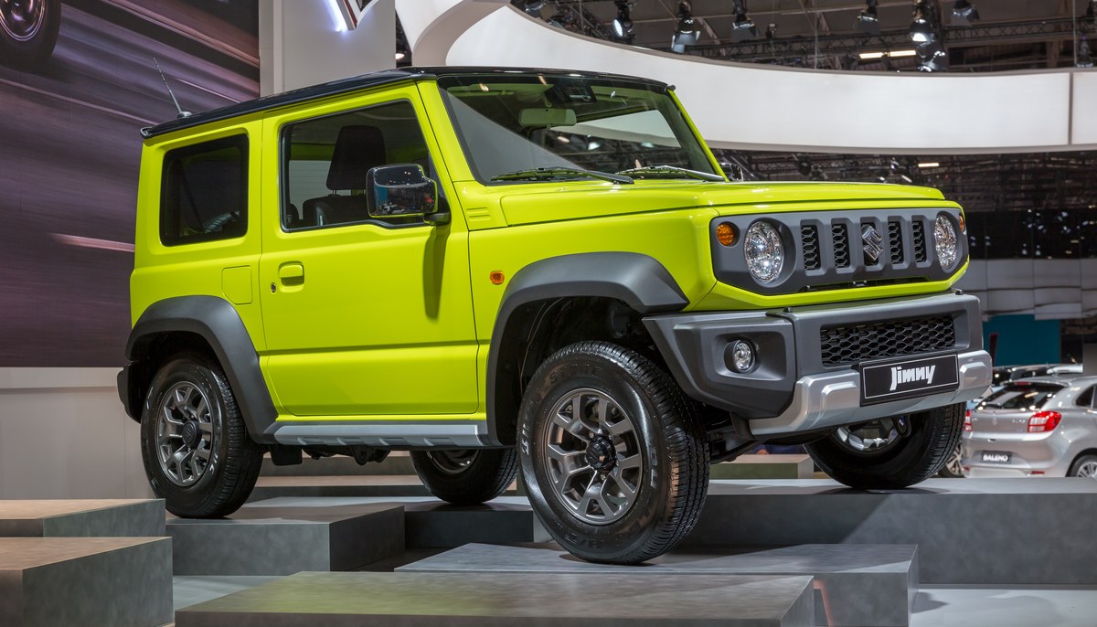 Салатово-жёлтый Suzuki Jimny четвёртого поколения на выставочном подиуме автосалона в Париже, вид спереди справа