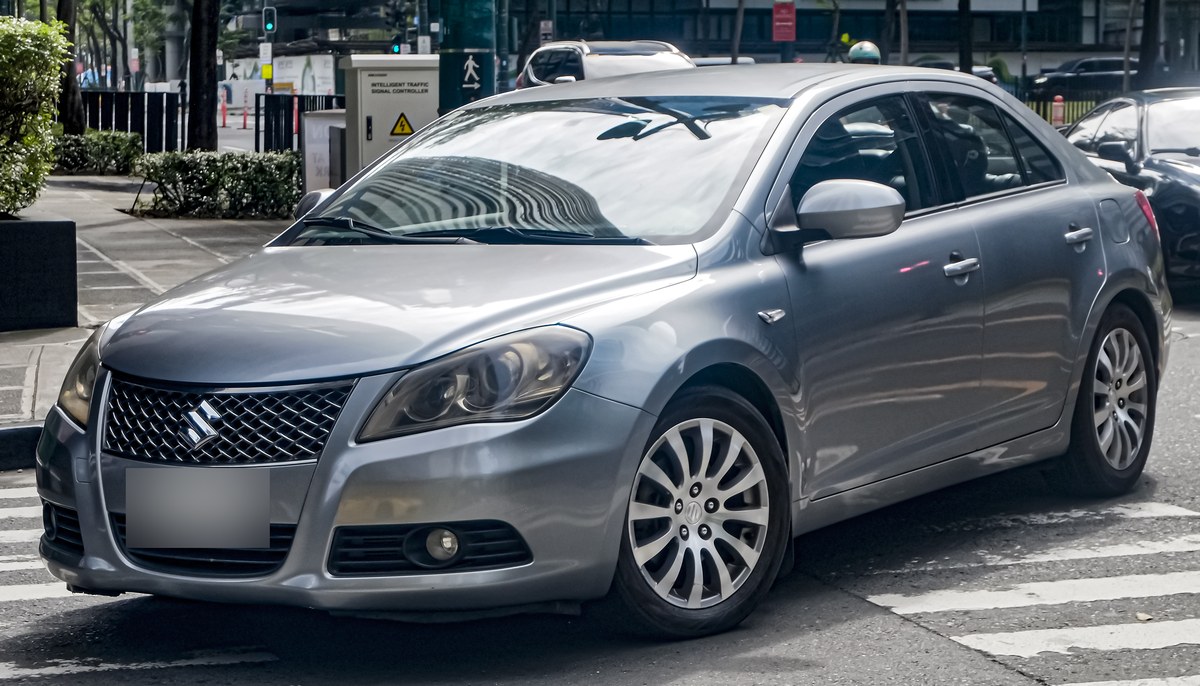 Серо-голубой седан Suzuki Kizashi, вид спереди слева, на городской улице
