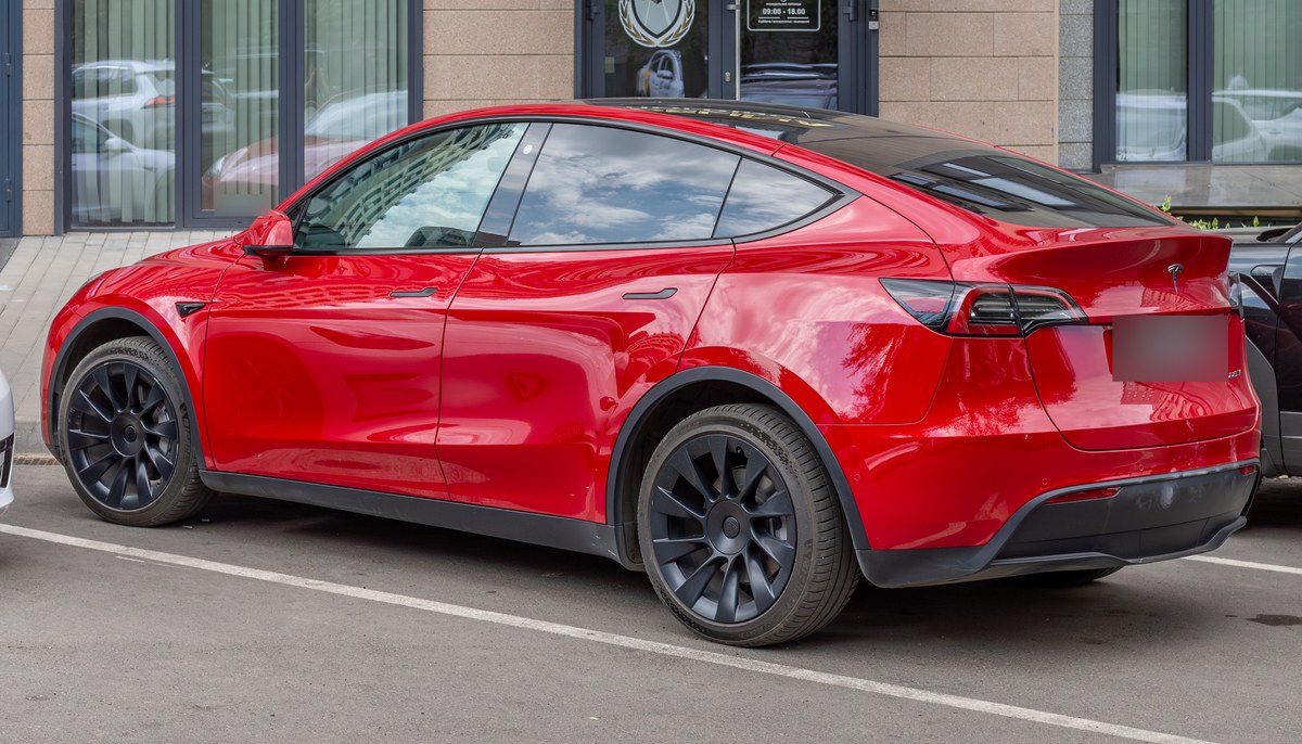 Красная Tesla Model Y первого поколения, вид сзади в три четверти, на городской улице в Алматы